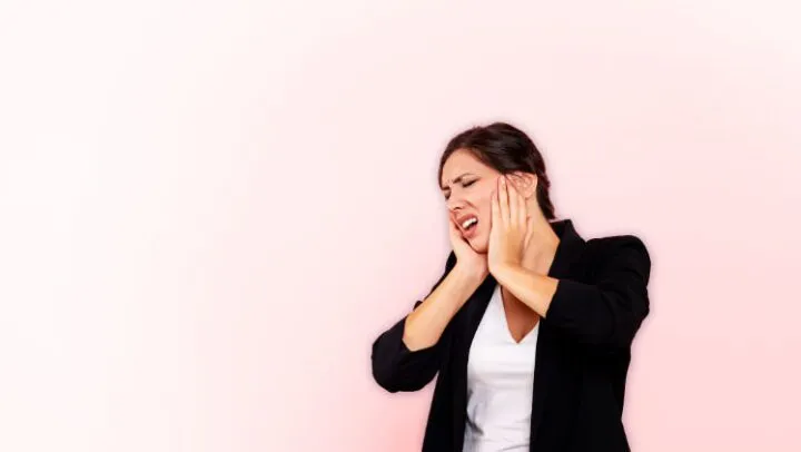 Imagem com mulher a agarrar o rosto simbolizando o sofrimento de quem padece de dor ou patologia orofacial facial (rosto, face, cabeça, pescoço)