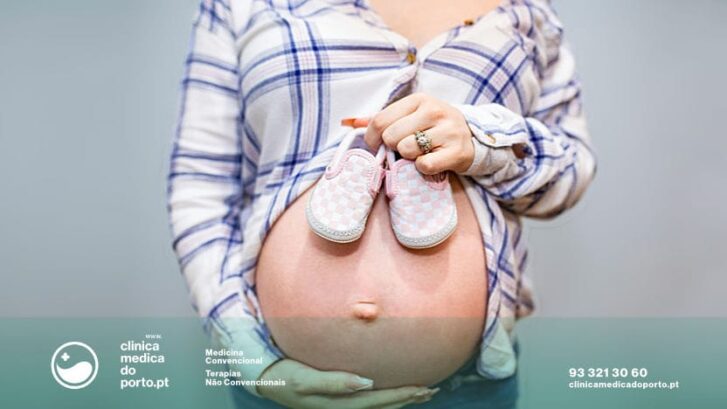Mulher grávida segura sapatinhos de bebé
