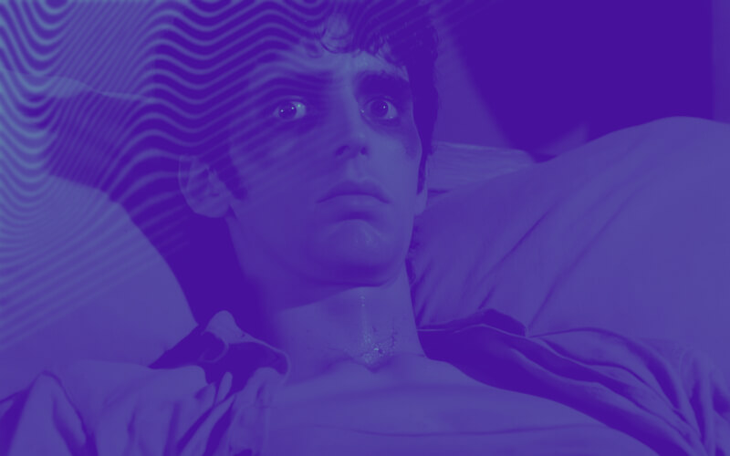 Homem na cama, com os olhos com enormes olheiras, em sinal de cansaço extrexmo ou insónia