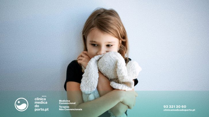 Imagem de menina com ar assustado olhando para baixo a segurar um peluche