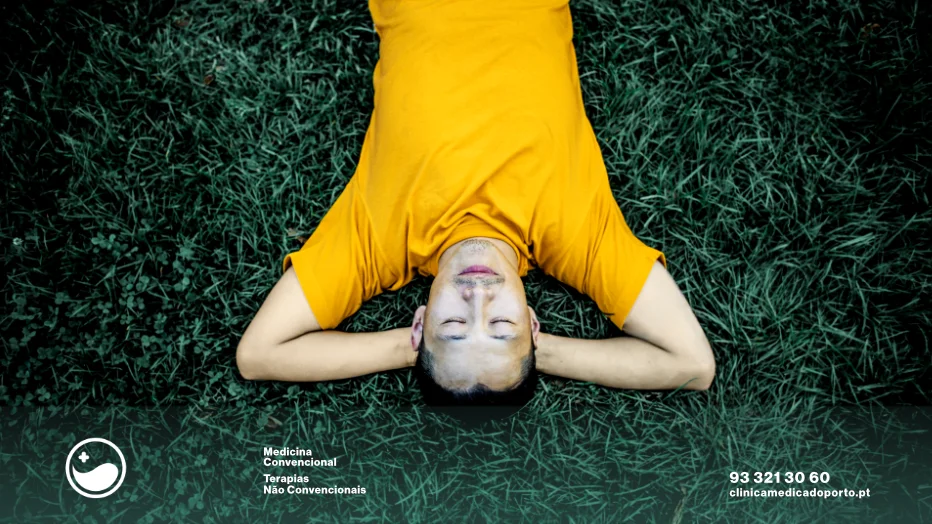 Pausas Sem Culpa: Recuperar o Foco em Vidas Hiperconectadas 3 Imagem de uma pessoa do sexo masculino deitado sobre um campo com erva, com os braços sobre a cabeça em posição de descanso